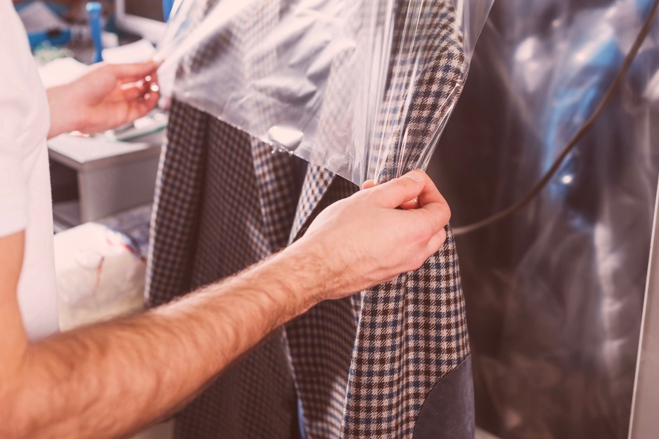 A man putting a cover over the top of a suit jacket