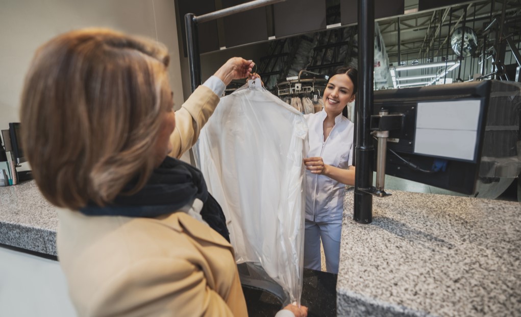 A lady collecting clothing in dry cleaners.